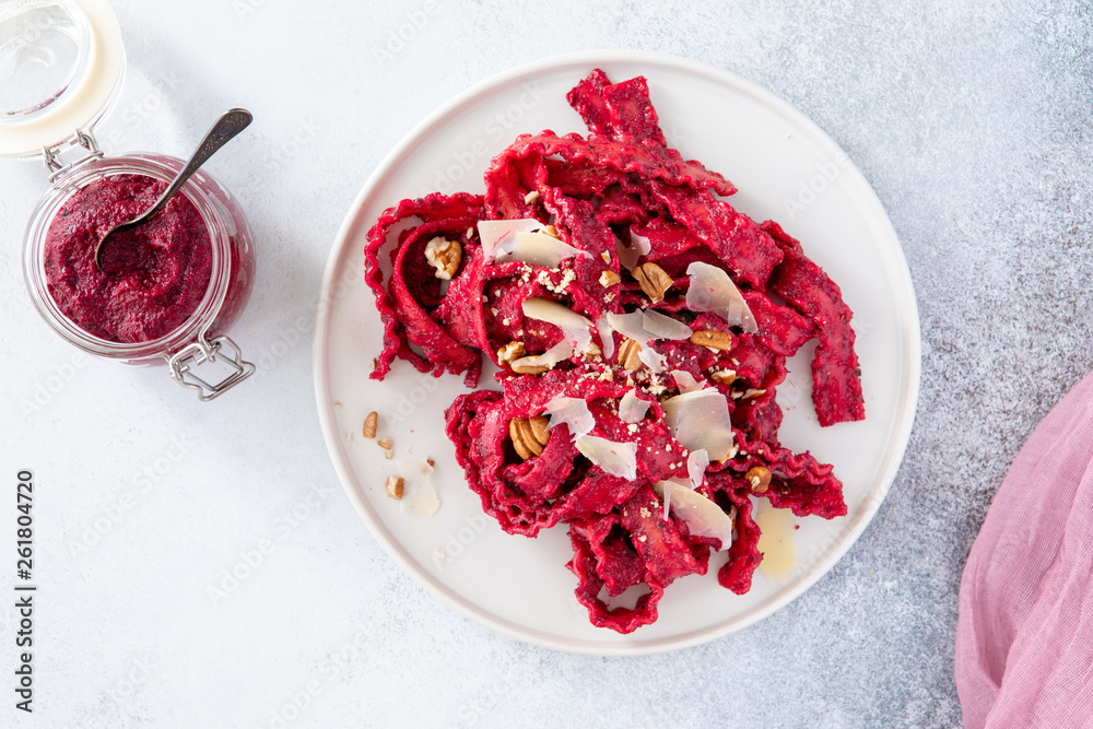 Top view of vegetarian mafaldine pasta with beet pesto sauce, walnut and parmesan cheese on a white background Top view of vegetarian mafaldine pasta with beet pesto sauce, walnut and parmesan cheese on a white background