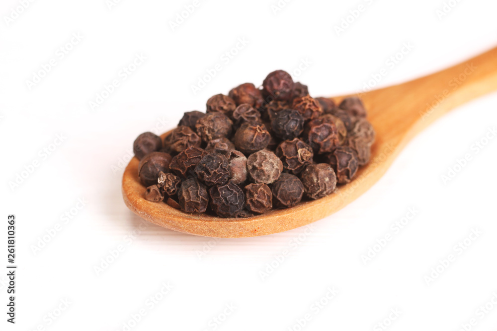 Wooden serving spoon full of black pepper spice isolated over the white background Wooden serving spoon full of black pepper spice isolated over the white background