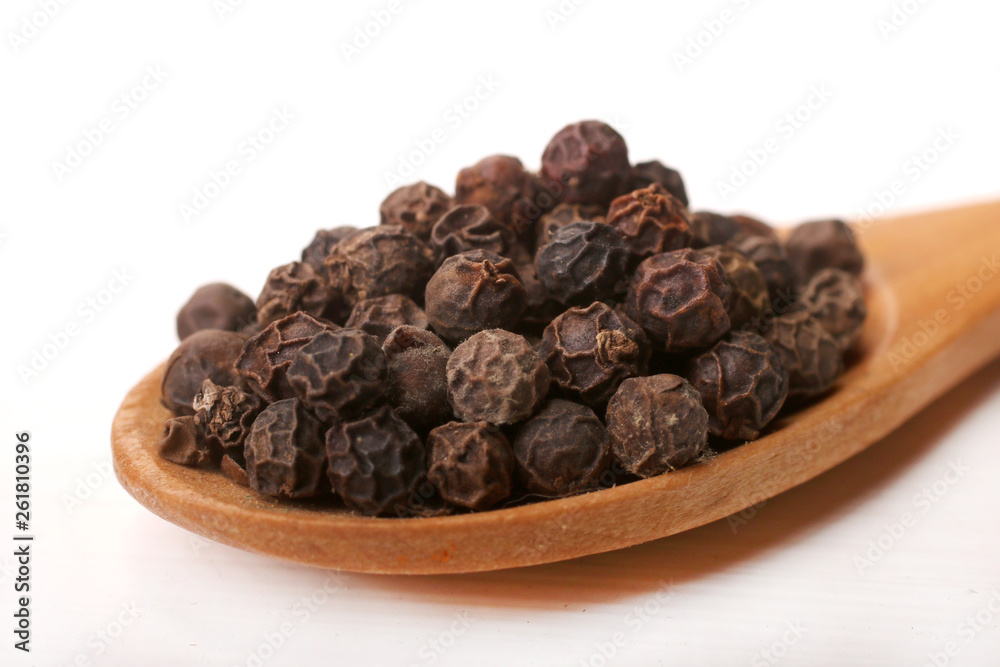 Wooden serving spoon full of black pepper spice isolated over the white background Wooden serving spoon full of black pepper spice isolated over the white background