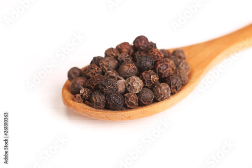 Wooden serving spoon full of black pepper spice isolated over the white background