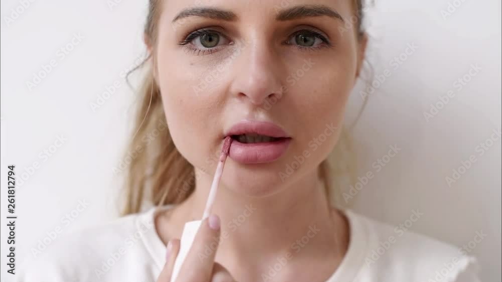 Closeup view of a young woman applying lipstick on her lips Closeup view of a young woman applying lipstick on her lips
