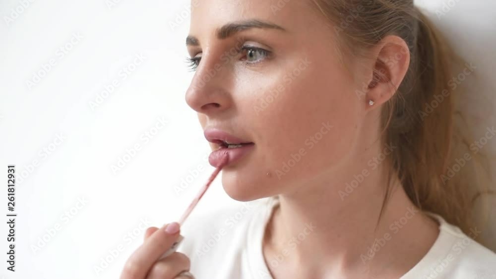 Closeup view of a young woman applying lipstick on her lips Closeup view of a young woman applying lipstick on her lips