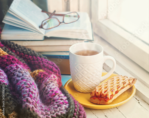 A сup of hot tea, stack of books and glasses on the background of a knitted blanket.  photo