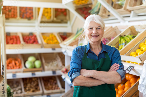Portrait of confident owner with arms crossed standing in small grocery store photo
