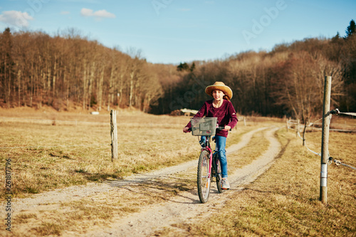 Cute little ten year old girl riding bicycle on countryside.