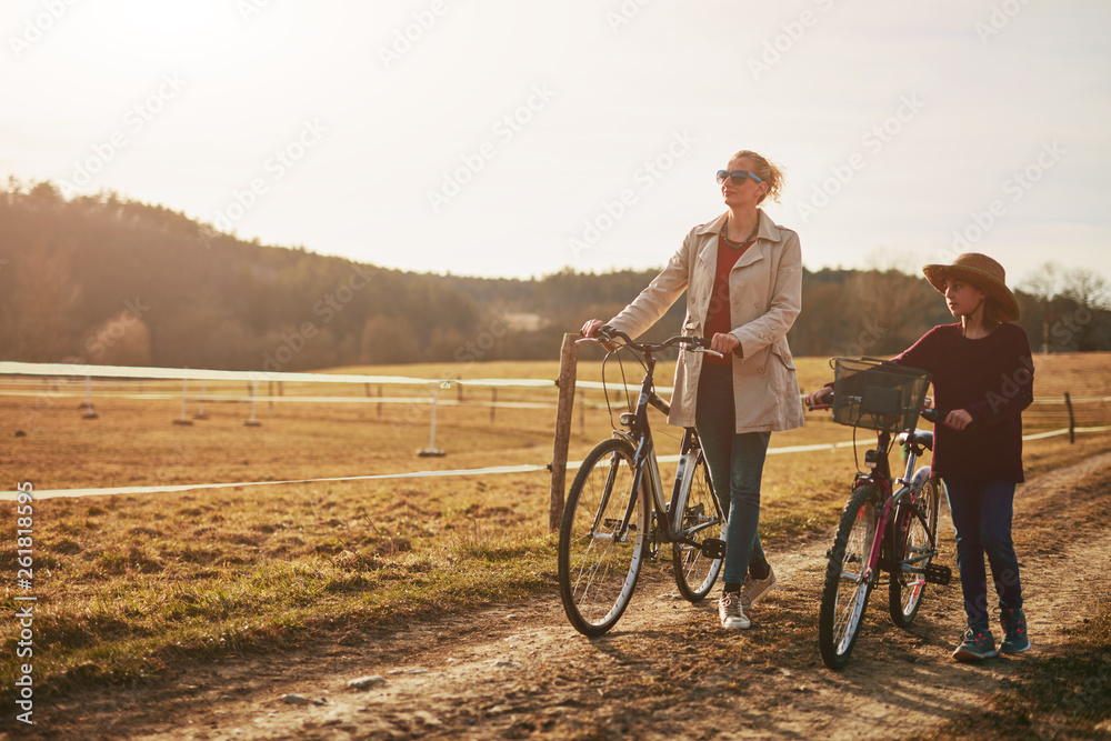 Obraz premium Mother and daughter with bicycles on countryside.