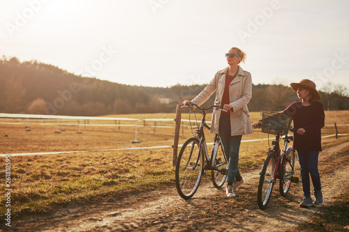 Mother and daughter with bicycles on countryside.