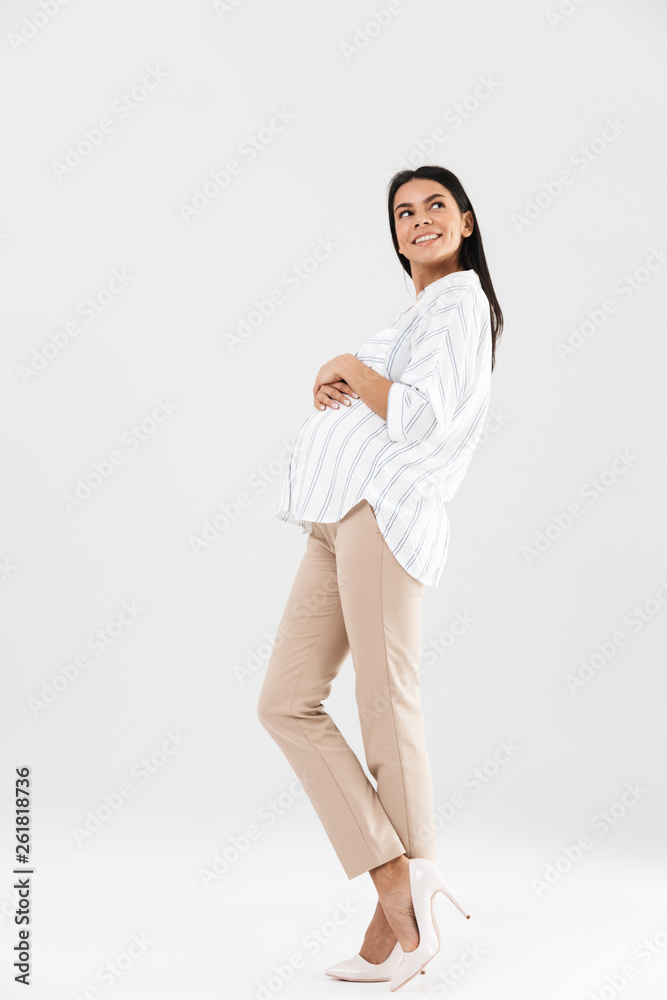 Full length photo of european pregnant businesswoman 30s smiling and touching her big tummy Full length photo of european pregnant businesswoman 30s smiling and touching her big tummy