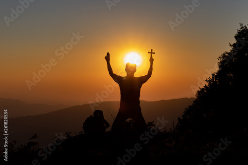Silhouette of woman praying with cross in nature sunrise background, Crucifix, Symbol of Faith. Christian life crisis prayer to god.