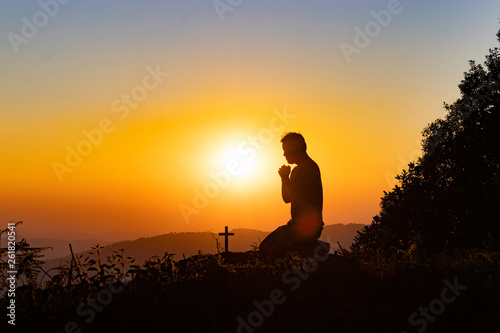 Silhouette of woman praying with cross in nature sunrise background, Crucifix, Symbol of Faith. Christian life crisis prayer to god.
