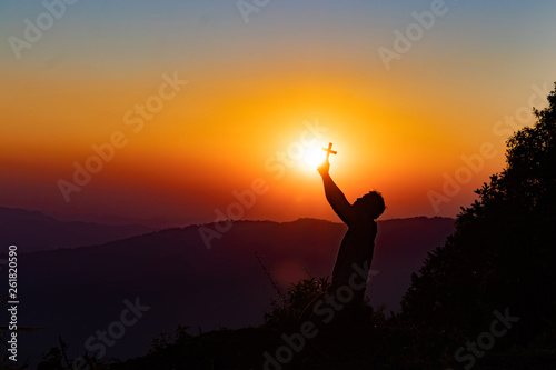 Silhouette of woman praying with cross in nature sunrise background, Crucifix, Symbol of Faith. Christian life crisis prayer to god.