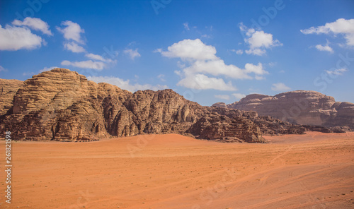 Wadi Rum Jordan Middle East panorama scenery desert landscape sand valley foreground and bare rocky mountain ridge background with vivid blue sky, travel planet and discovery concept photography