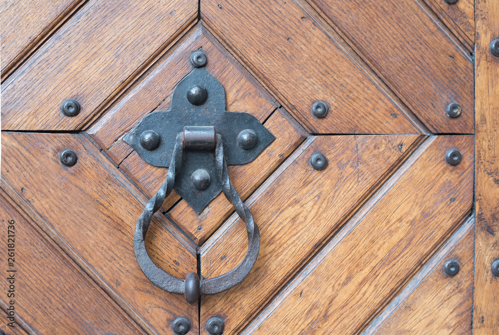 Forged metal door handle with a ring on a wooden door Forged metal door handle with a ring on a wooden door