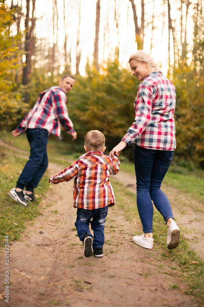 Fototapeta premium Little cute son playing with parents in forest