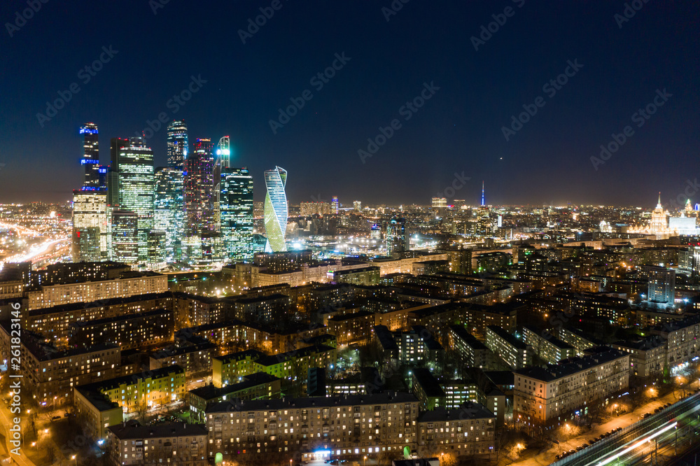 Obraz premium high-rise buildings and transport metropolis, traffic and blurry lights of cars on multi-lane highways and road junction at night in Moscow.