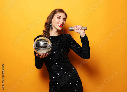 woman in evening dress holding microphone and disco ball