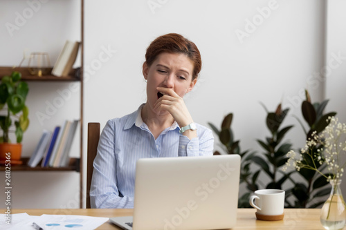 Vászonkép Sleepy bored businesswoman yawning at workplace feeling deprived in office
