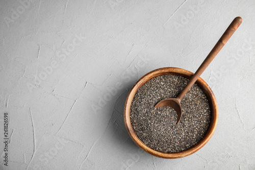 Bowl and spoon with chia seeds on grey background, top view. Space for text