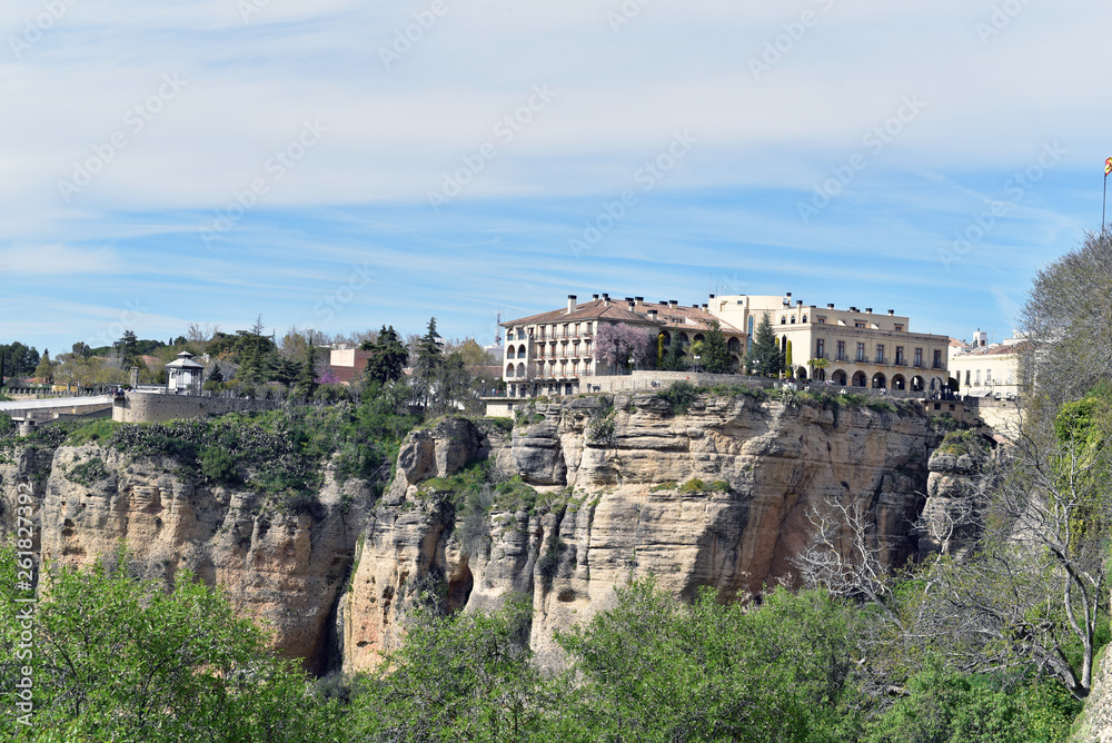 Landscape of white house on the green edges of steep cliffs with mountains in the background, Ronda, Spain