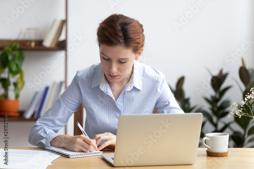 Focused millennial business woman office worker make notes planning work