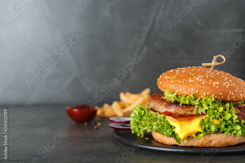 Plate with tasty burger on table. Space for text