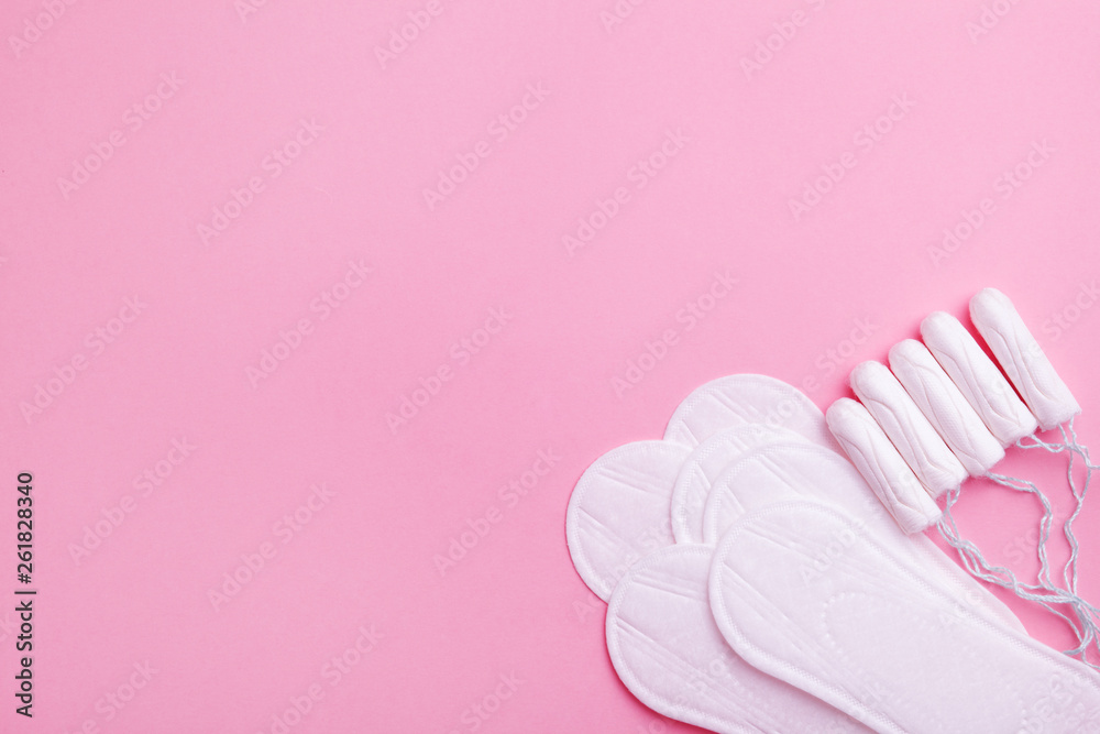 women intimate hygiene products - sanitary pads and tampons on pink background, copy space