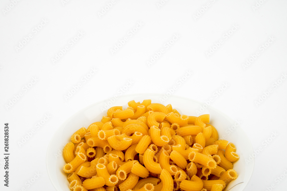 Uncooked macaroni in a bowl isolated on white background with space for text, flat lay concept. Uncooked macaroni in a bowl isolated on white background with space for text, flat lay concept.