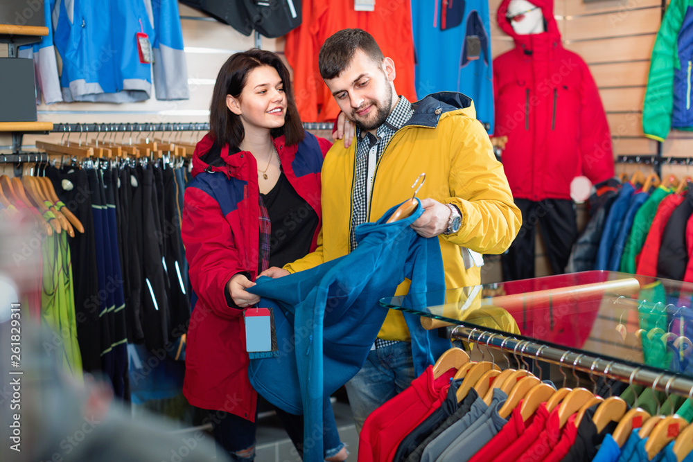 Couple examining track jackets in sports clothes store