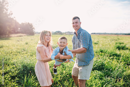 Mother and father swinging son in sunnny summer day