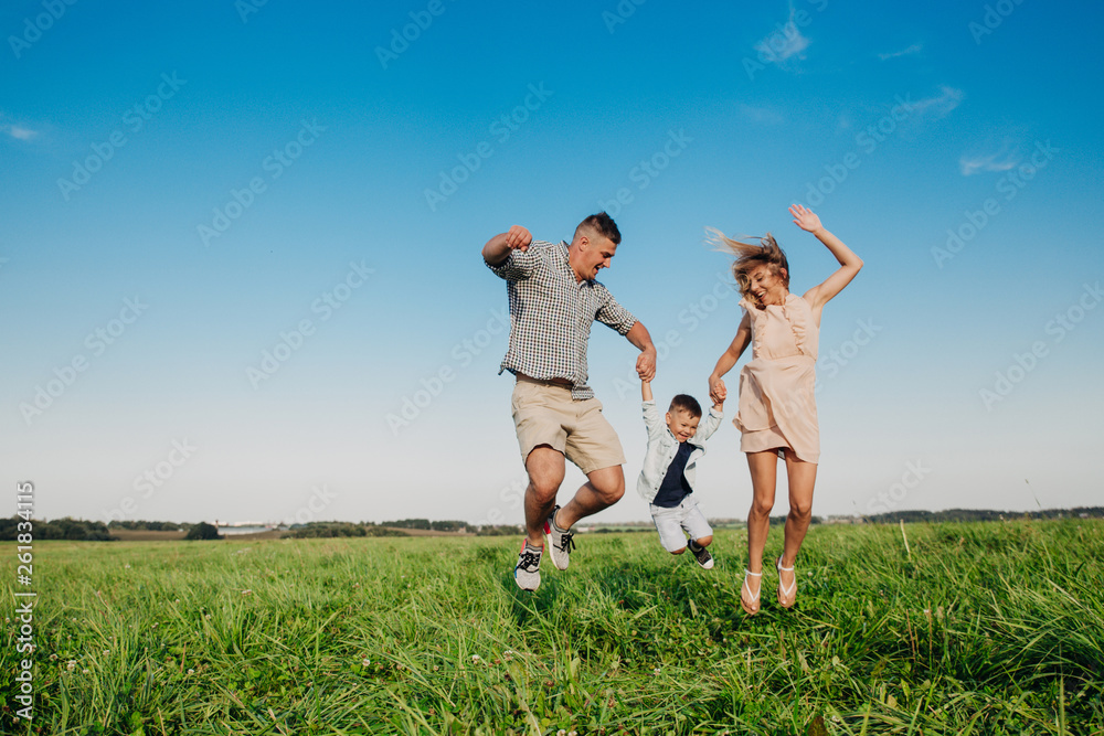 Happy family jumping together in the field in sunny day Happy family jumping together in the field in sunny day