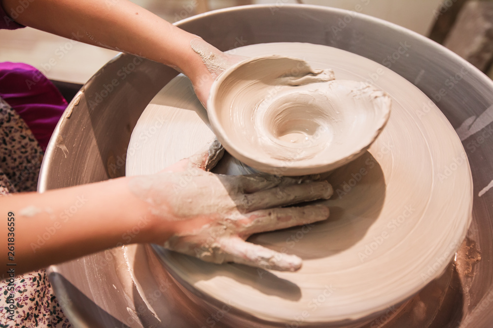Fototapeta premium young potter hands working with clay on pottery wheel