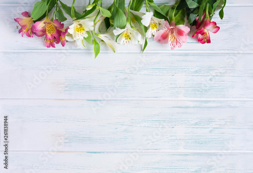 Template birthday greeting card. Light wooden background with flowers of astormia in pink and white. The basis for the congratulatory banner. Banner with flowers and copispeys.