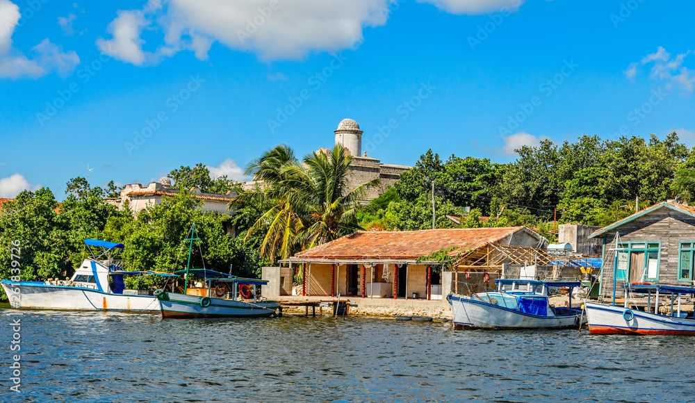Cuban fishing boats and village houses with Jagua Spanish castle walls in the background, Cienfuegos province, Cuba
