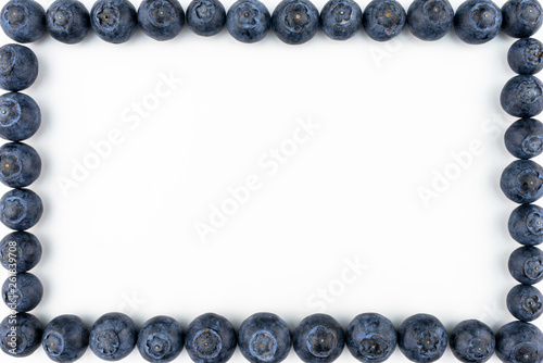Frame made from fresh blueberries, top view, flat lay, isolated on a white background with copy space in the middle.