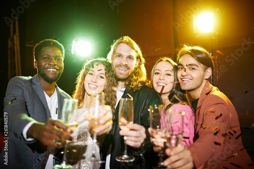 Billede på lærred Group of jovial young multi-ethnic friends in stylish outfits standing with flut
