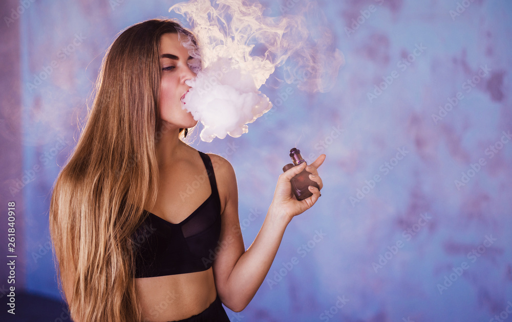 Trendy new vaping device, smoke e-liquid instead of nicotine cigarettes. Tobacco free e-juice. Vaping concept. Modern girl smoking Stock Photo | Stock