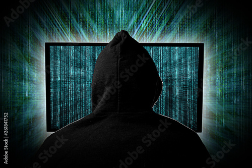 hacker  behind glowing computer monitor display in front of green source binary code background internet cyber hack computer concept photo