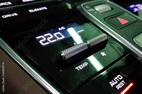 Climate control panel in the interior of the premium car. The screen temperature is set at 22 degrees. Black glossy surface.