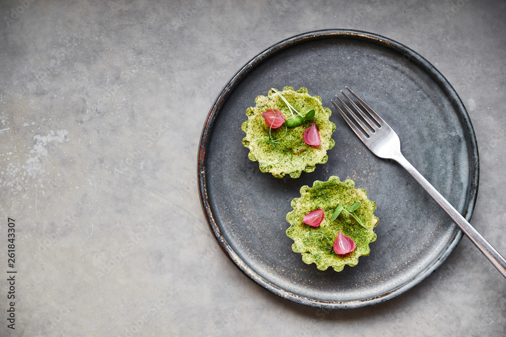 Two tartlets on a dark plate in a restaurant. Gourmet dish. Two tartlets on a dark plate in a restaurant. Gourmet dish.