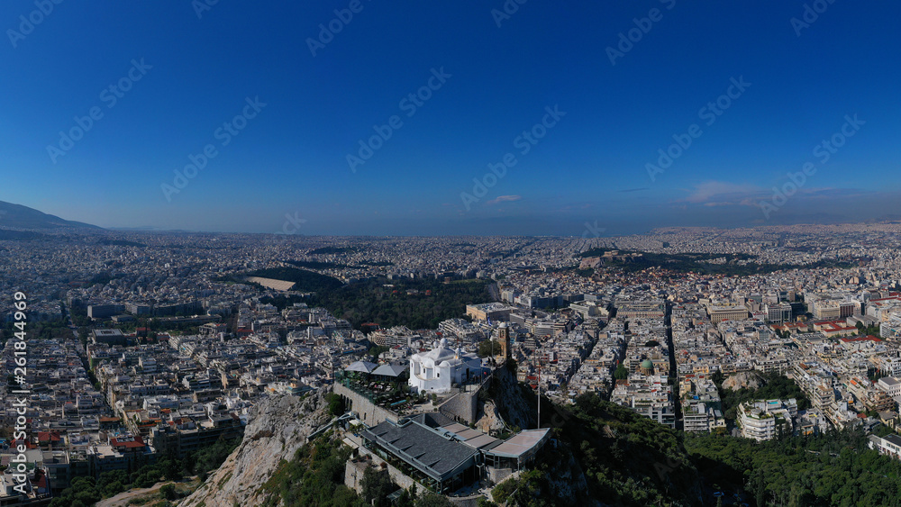 Obraz premium Aerial drone panoramic photo of iconic Saint George Lycabettus chapel as seen from top of hill, all Athens cityscape and Acropolis hill at the background, Athens historic centre, Attica, Greece