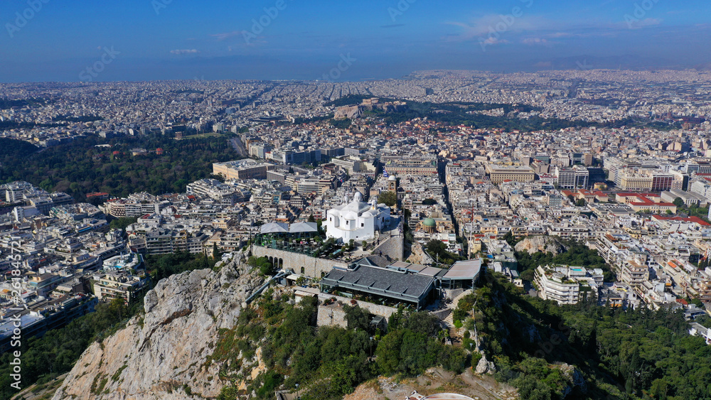 Aerial drone panoramic photo of iconic Saint George Lycabettus chapel as seen from top of hill, all Athens cityscape and Acropolis hill at the background, Athens historic centre, Attica, Greece
