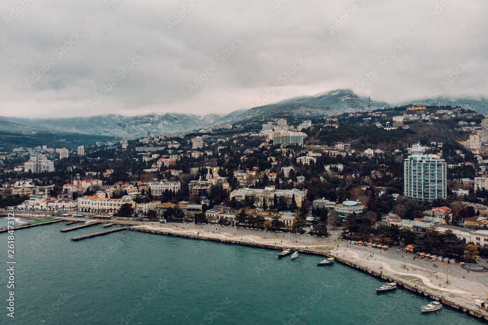 Aerial view of Yalta embankment from air in winter day. City on mountains and coastline with buildings and beautiful nature