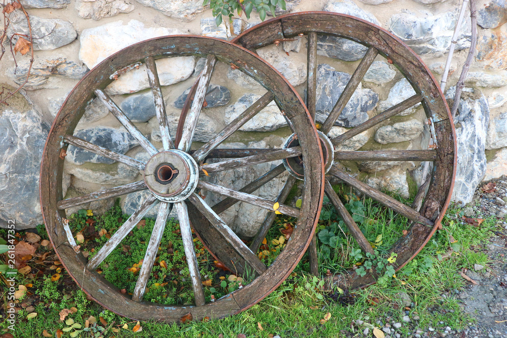 Two old horse wagon wooden wheels placed on a stone wall 