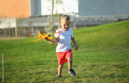Young boy playing airplane on the green grass