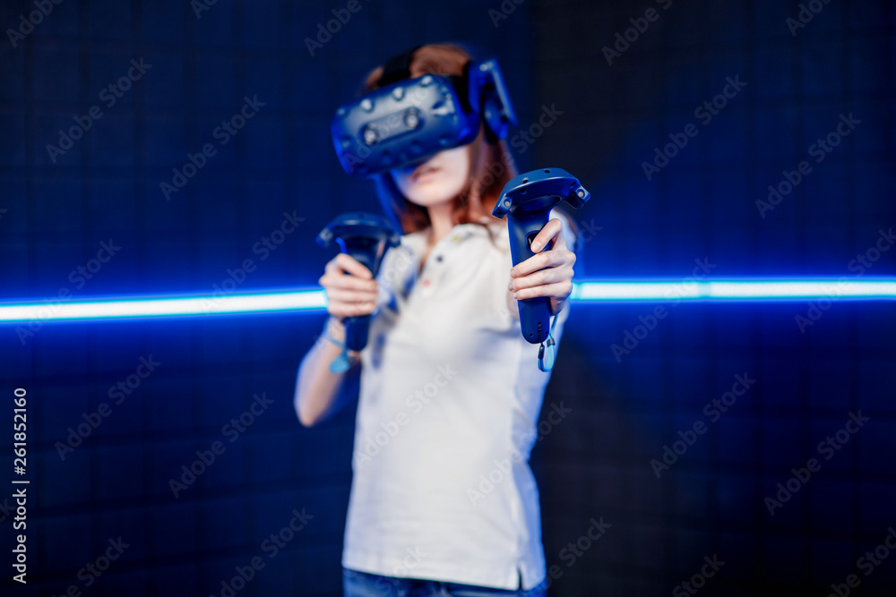 A young girl in a virtual reality helmet in the game room is playing a video game. A young girl in a virtual reality helmet in the game room is playing a video game.