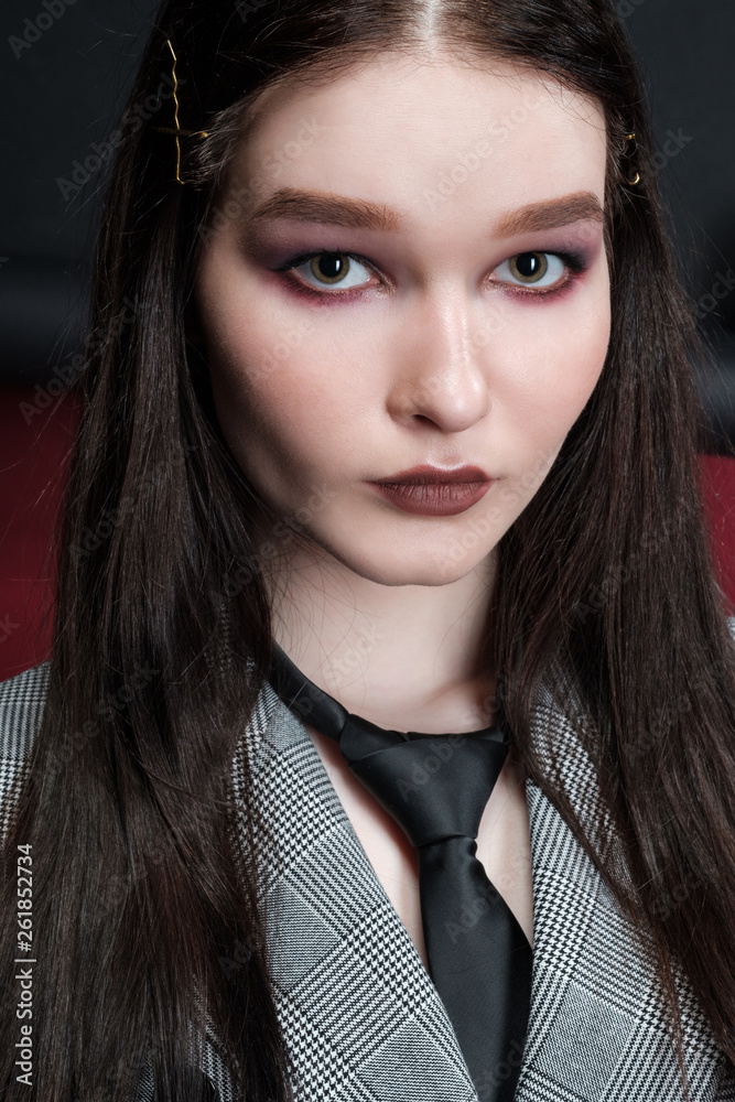 Young beautiful female fashion model in a business stylish suit on a red and black background. Young beautiful female fashion model in a business stylish suit on a red and black background.
