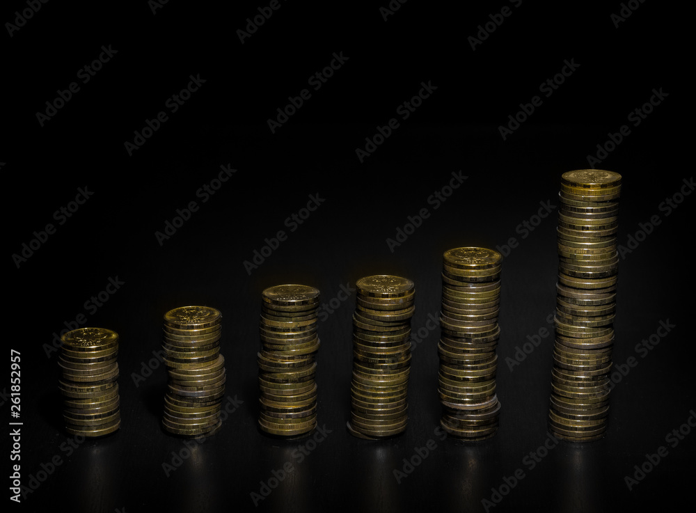 Gold coin stack isolated on dark background. Stacks of gold coins of various heights. Vertical bar chart. Gold coin stack isolated on dark background. Stacks of gold coins of various heights. Vertical bar chart.
