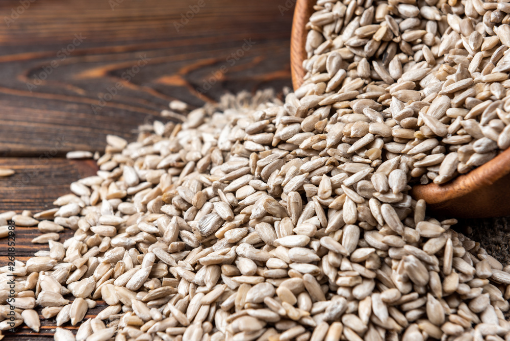Obraz premium Sunflower seeds on dark wooden background.