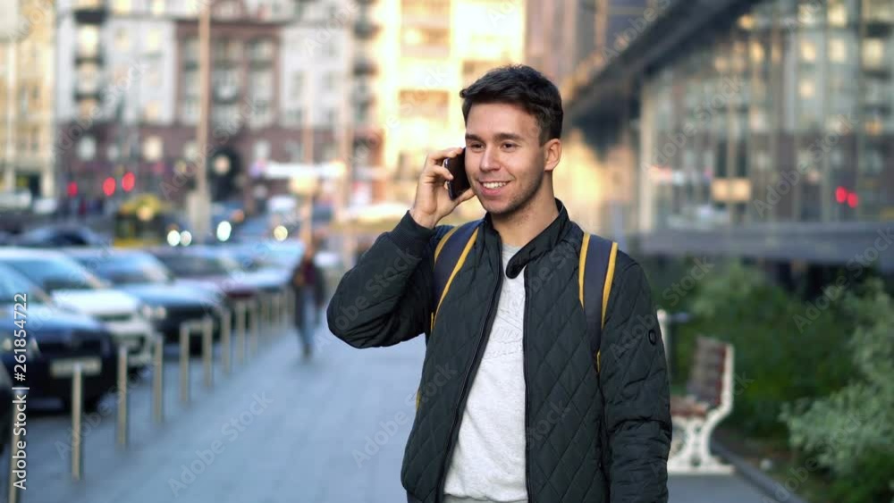 Young Attractive Man Speaking by Phone in the evening city street with bokeh light effect Young Attractive Man Speaking by Phone in the evening city street with bokeh light effect