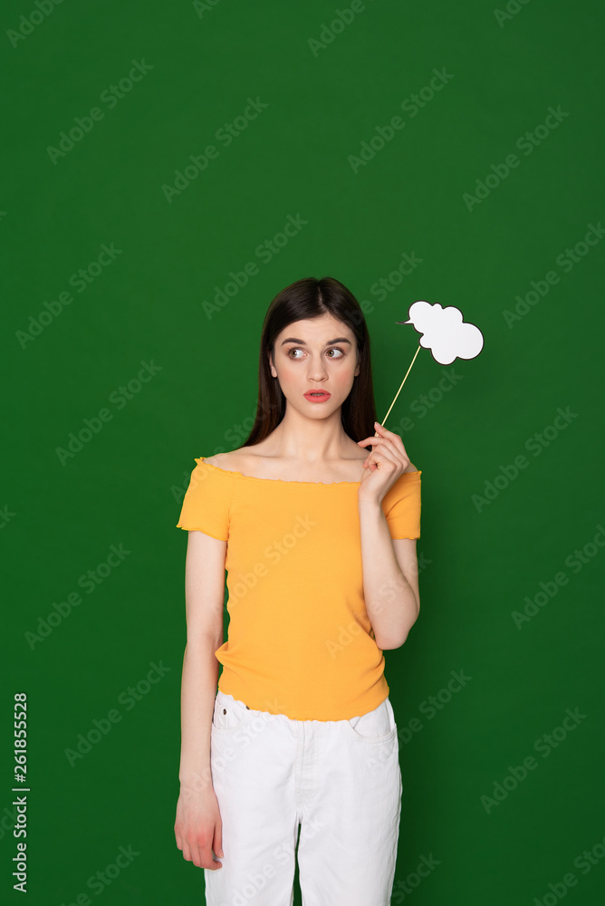 Wondering brunette young girl isolated on green